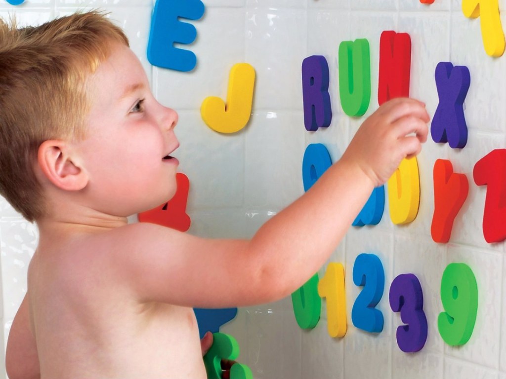 little boy playing with letters in a bath tub