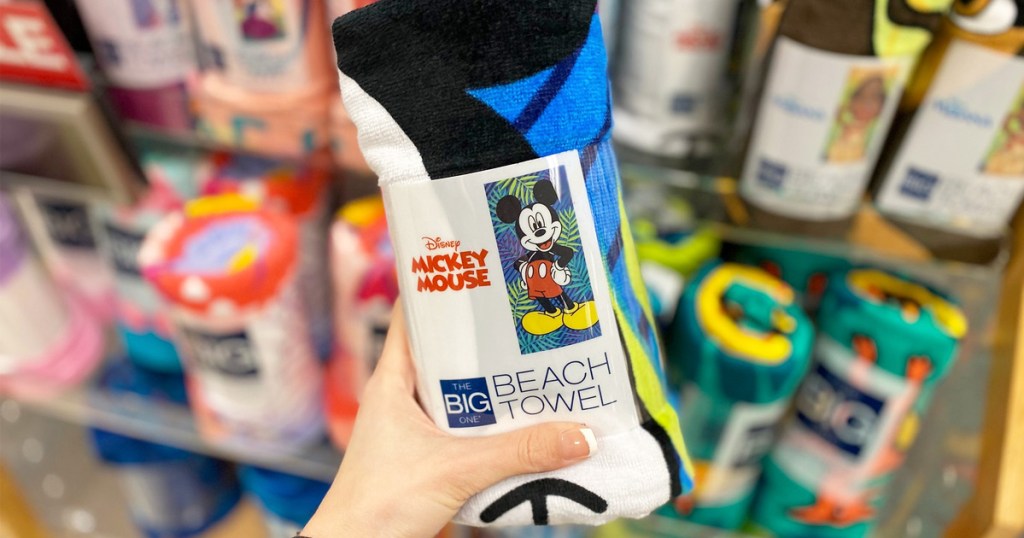 person holding up a blue rolled up mickey mouse printed beach towel
