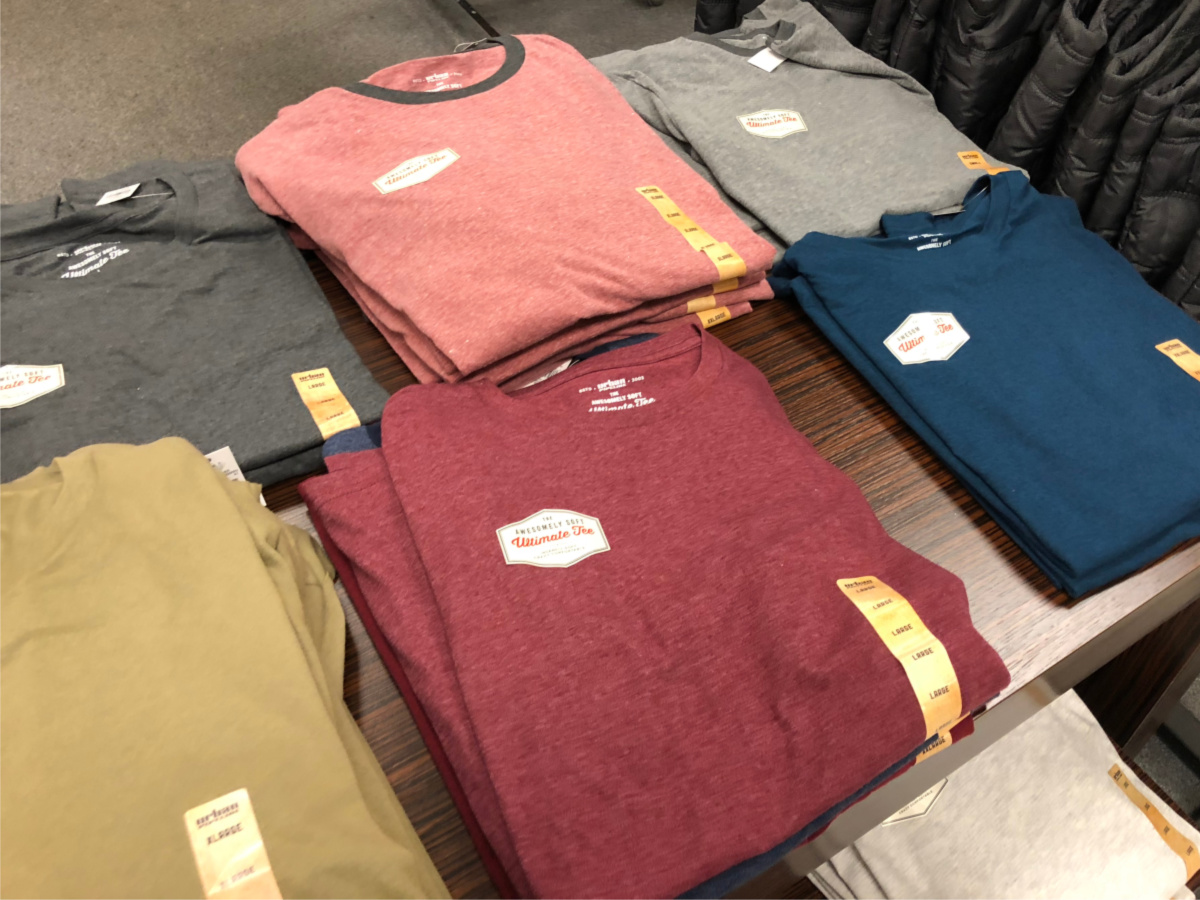 various colored men's tees folded on wood table in store