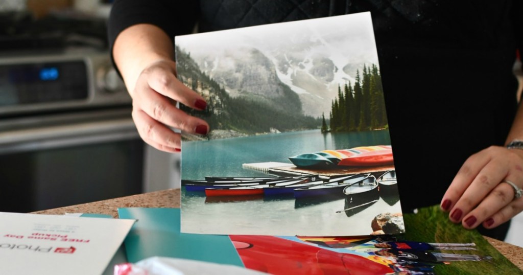 hand holding a photo print of a lake with boats on it