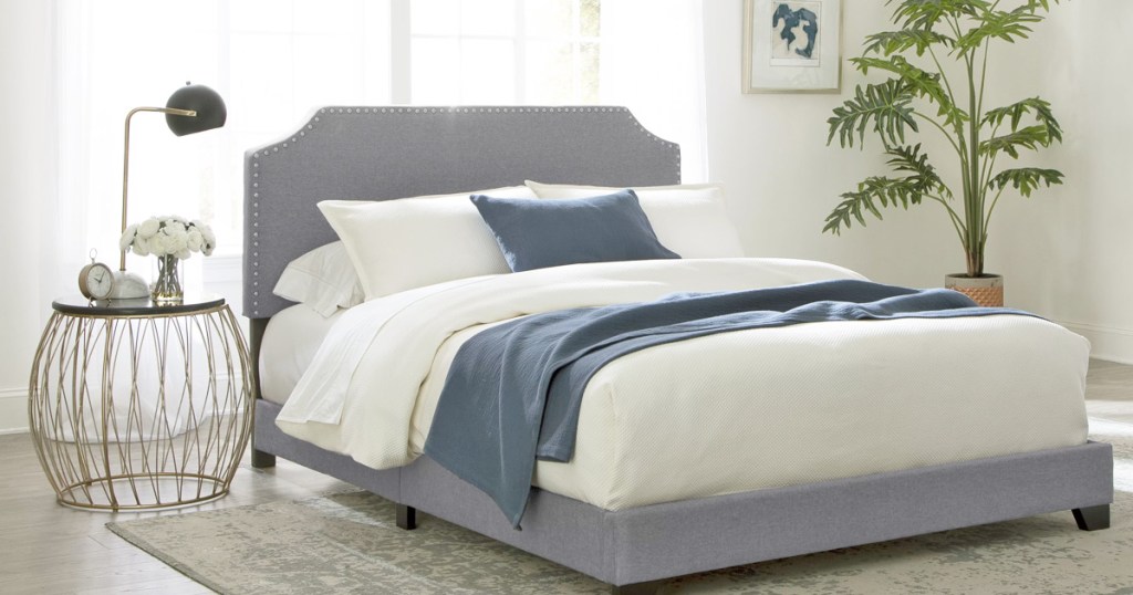 grey upholstered headboard and frame with white bedding and navy blue throw blanket and pillow in bedroom