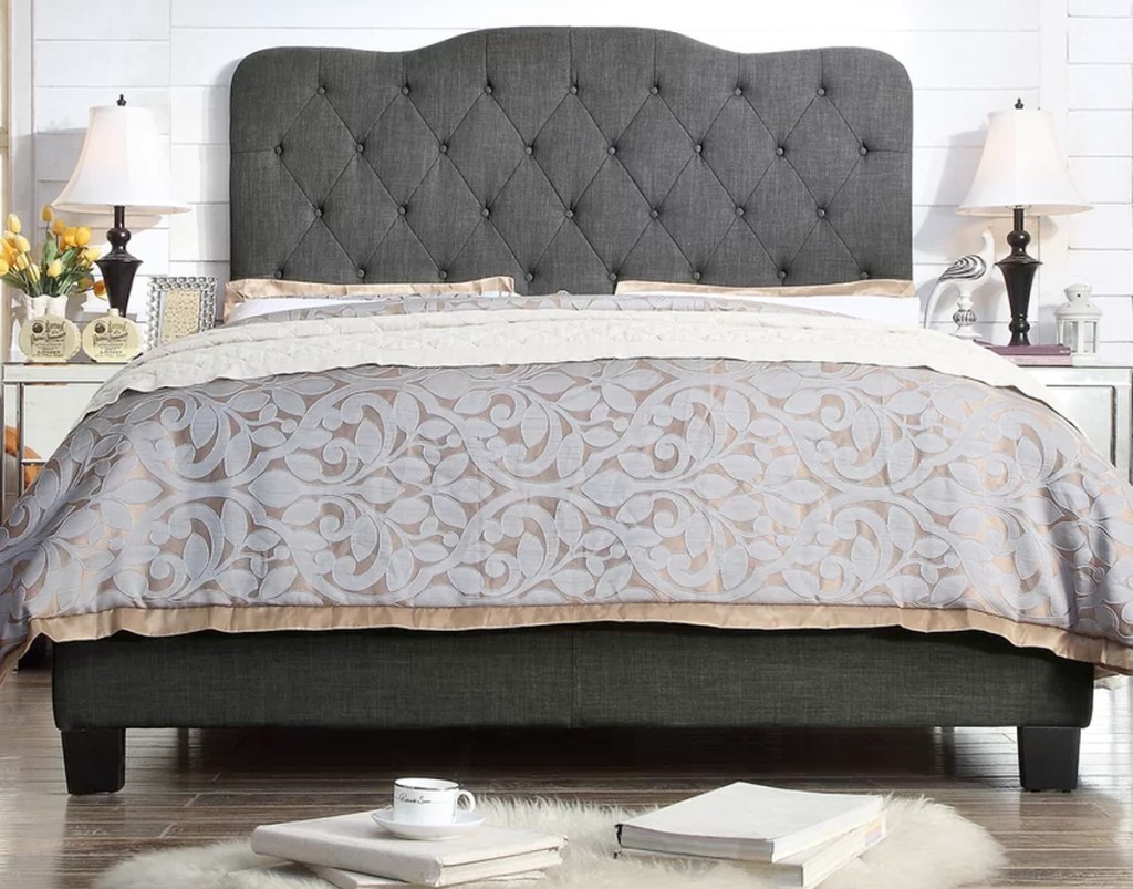 dark grey upholstered headboard and bed frame with floral print bedding on bed