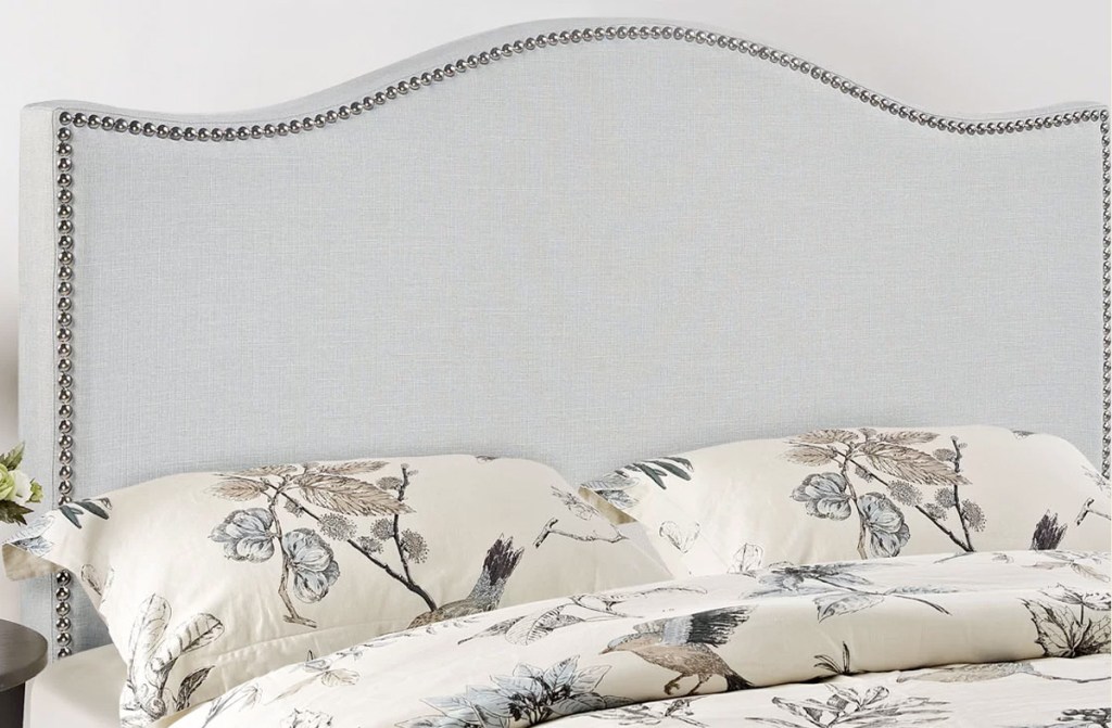 light grey upholstered headboard with nails along trim