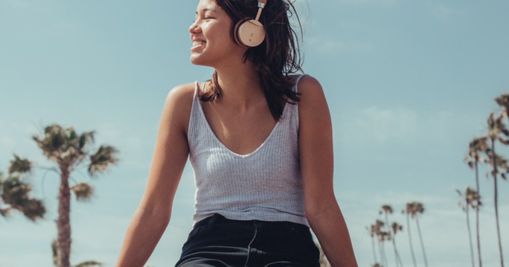 woman with headphones on and palm trees in background