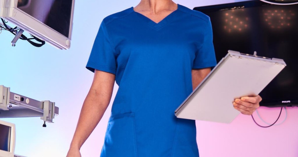 Woman wearing blue scrub top holding a clipboard in her hands