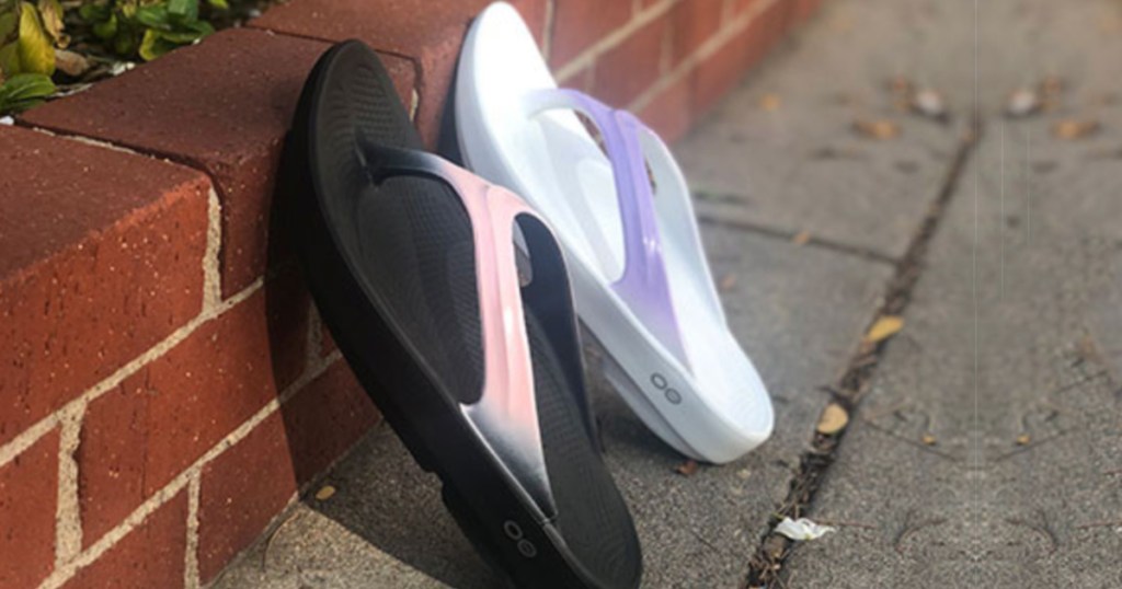 Women's Oofos OOlala Luxe Recovery Sandals leaning up against a brick wall outside