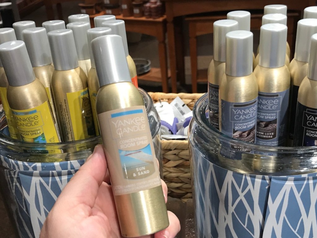 hand holding fragrance spray in front of display in store