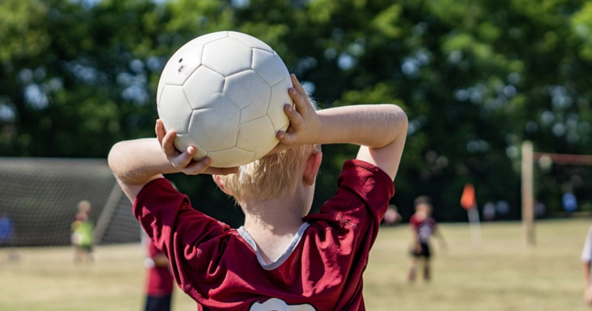 boy playing soccer and throwing an adidas soccer ball