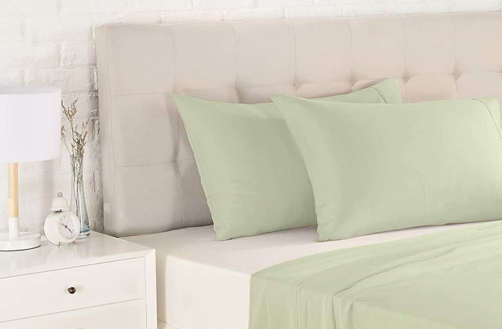 bed made with light green sheets and pillowcases