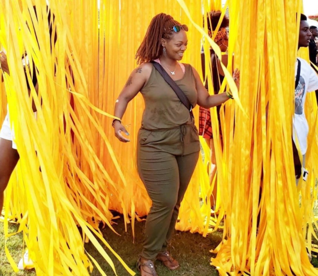 Woman wearing green jumpsuit standing around tons of yellow streamers