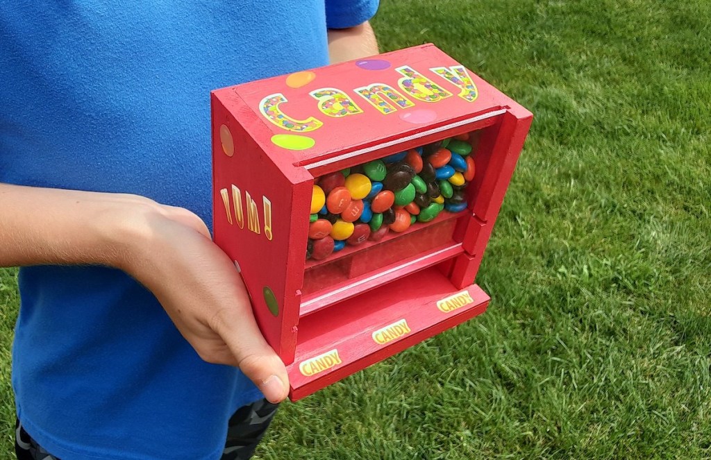 kid holding red candy m&m dispenser 
