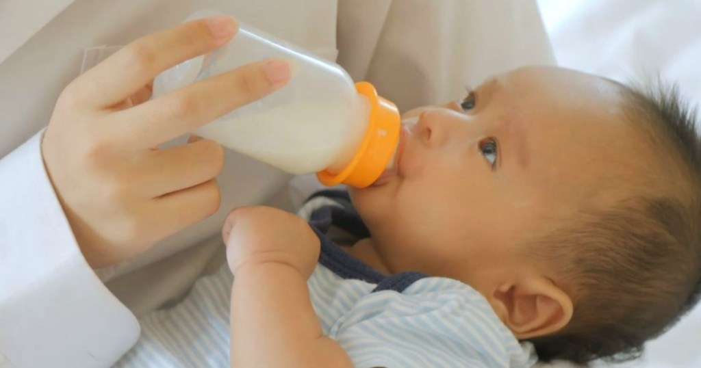 someone feeding new baby with bottle