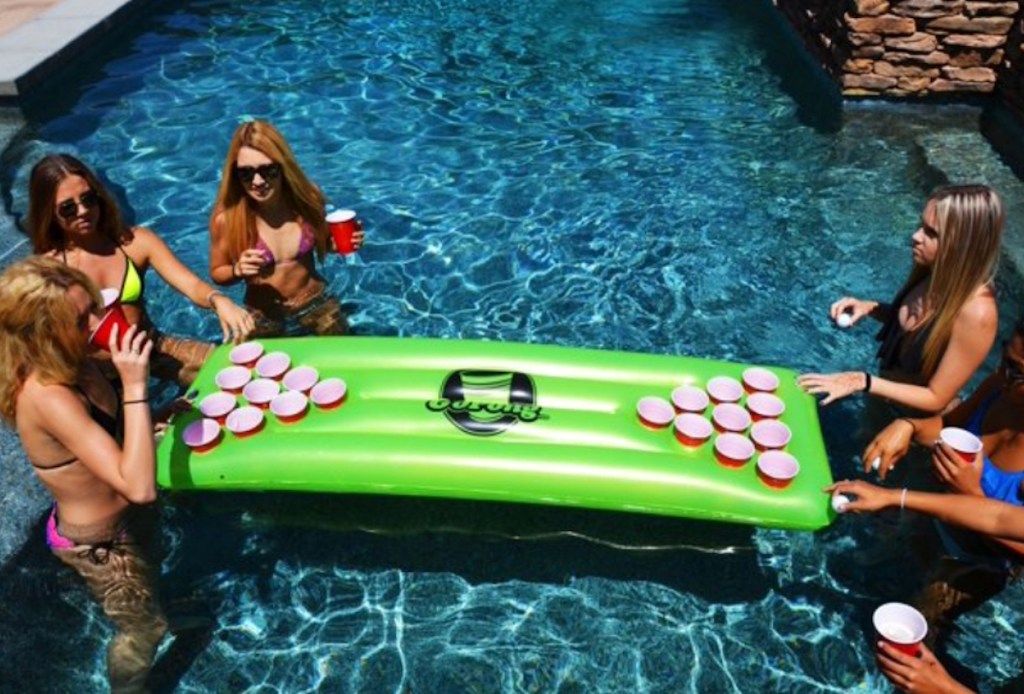 people in pool surrounding green pool float with cups