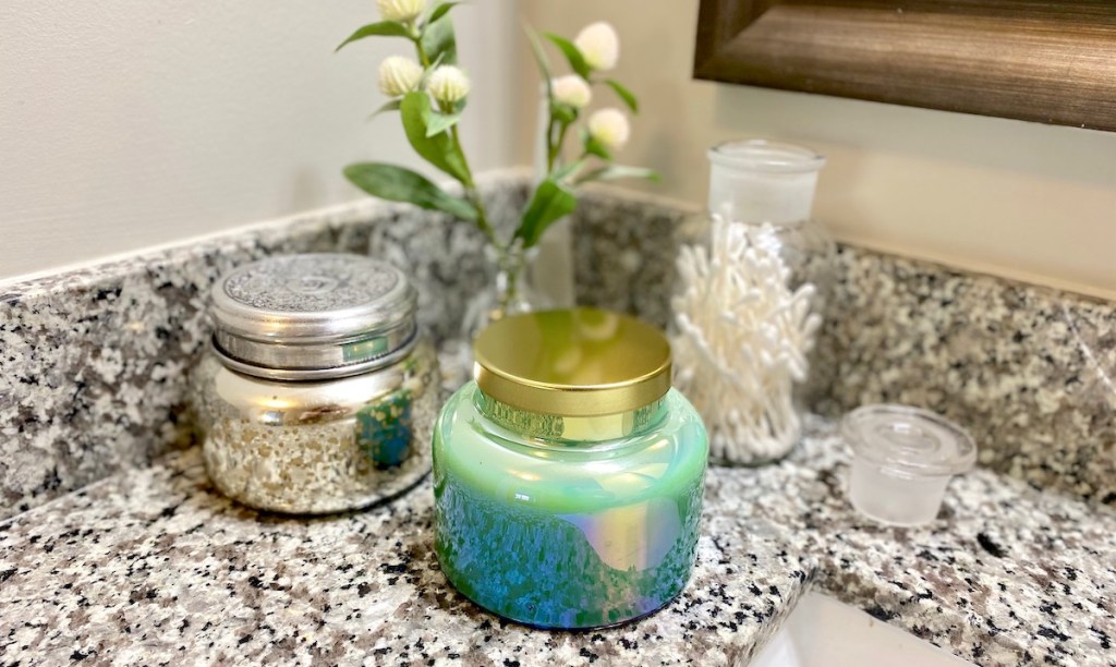 blue and silver candles sitting on granite countertop with flowers and jar of qtips 
