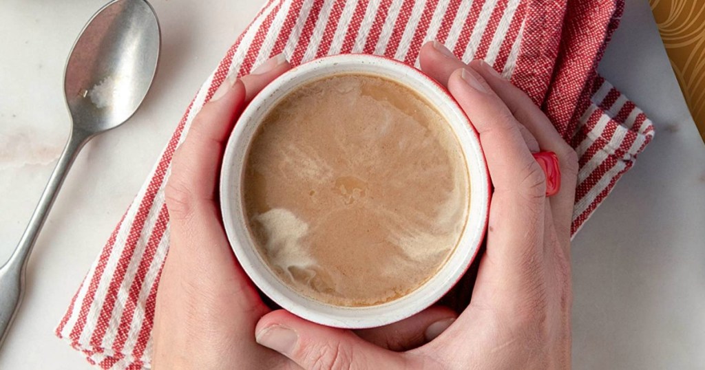 hands around cup of coffee with cream