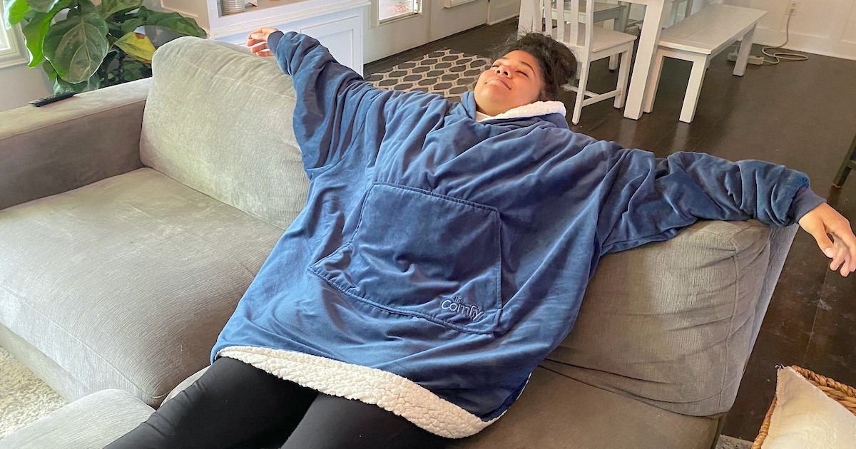 woman laying on couch wearing a blue oversized blanket 