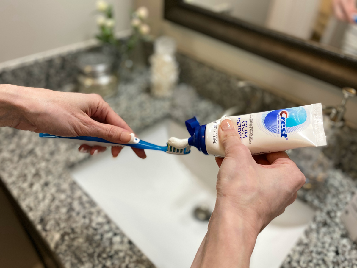 woman squeezing toothpaste on brush