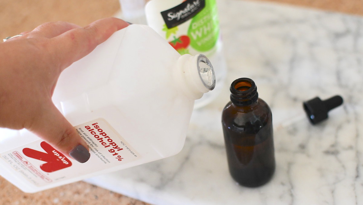 hand pouring rubbing alcohol into brown dropper bottle