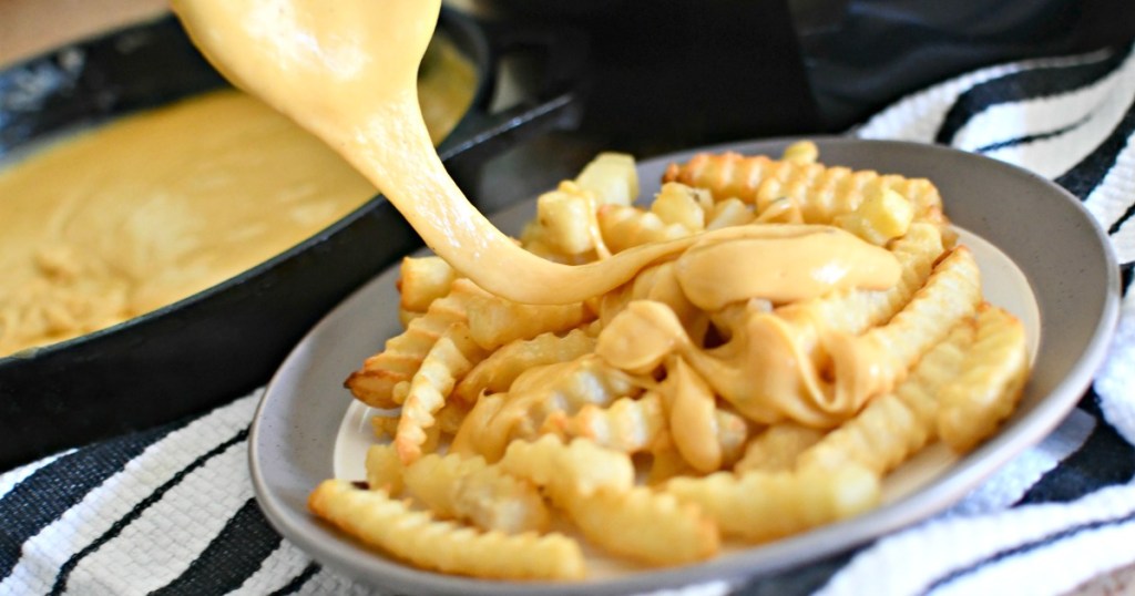 Drizzling cheese sauce on top of fries for cheese fries 
