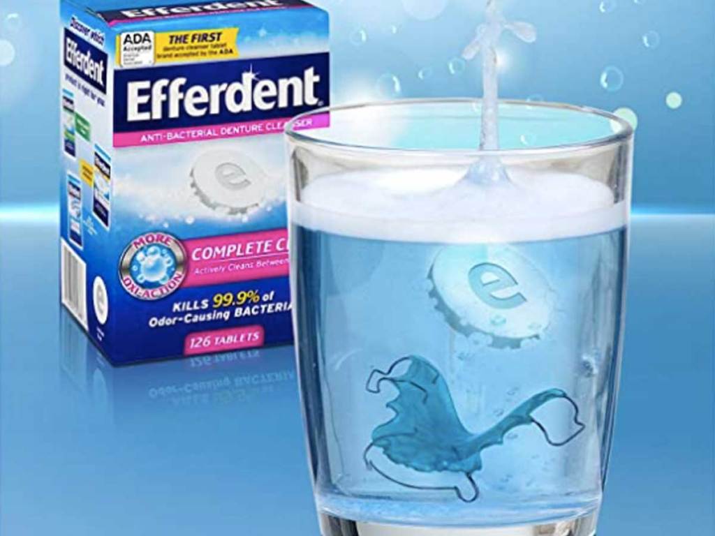 box of efferdent next to a glass of water with a retainer in it