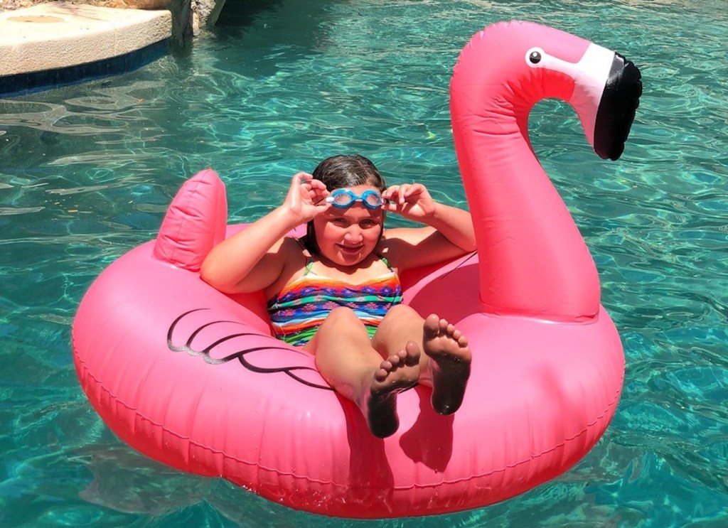 girl floating on pink flamingo pool float