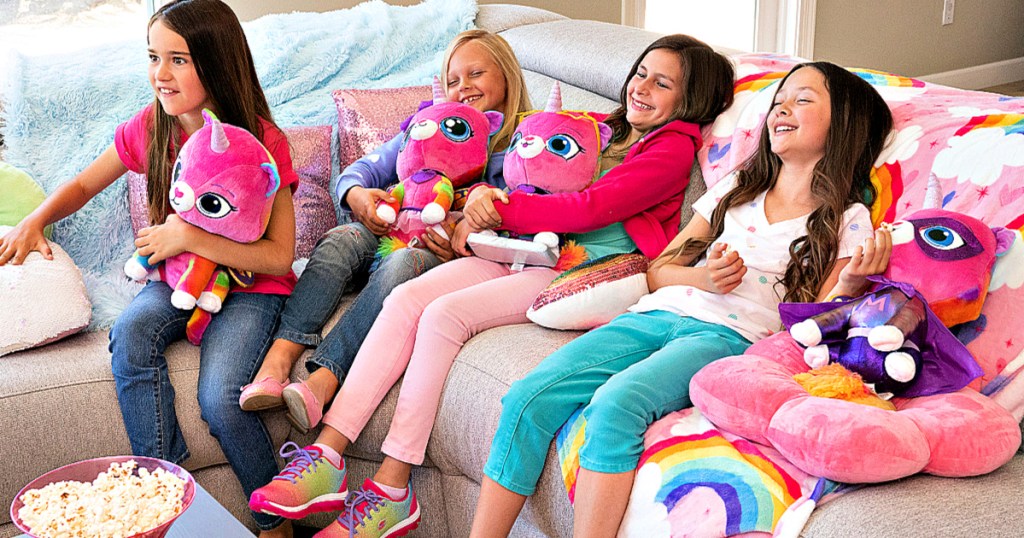 girls holding rainbow butterfly unicorn kitty plush on couch