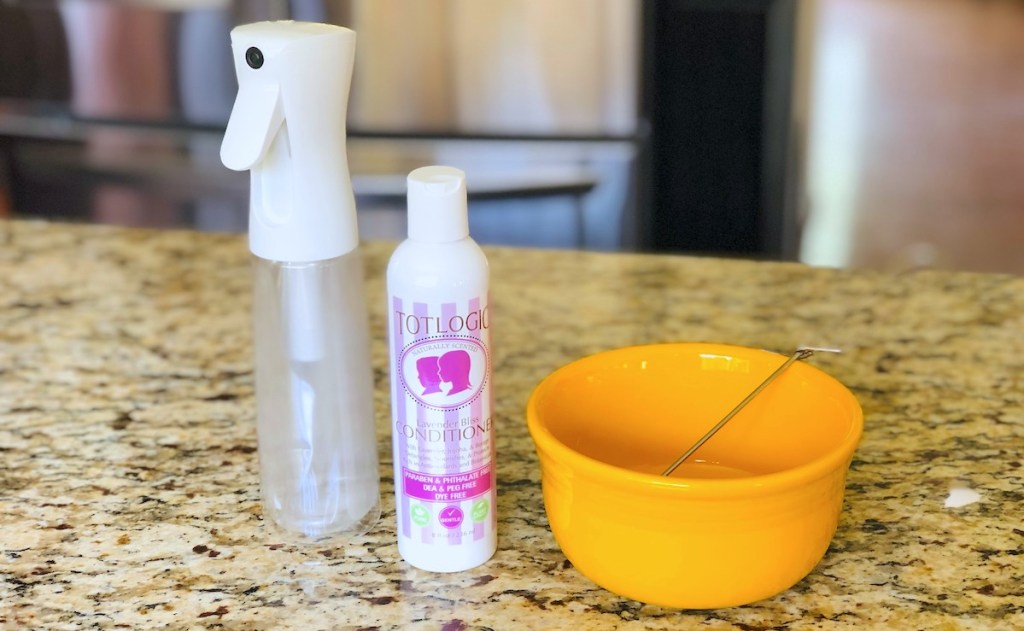 clear spray bottle and conditioner sitting on counter with yellow bowl