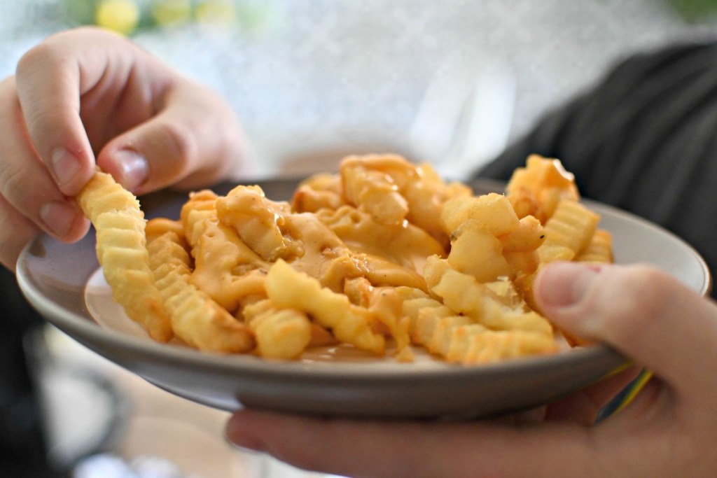 holding a plate of homemade cheese fries
