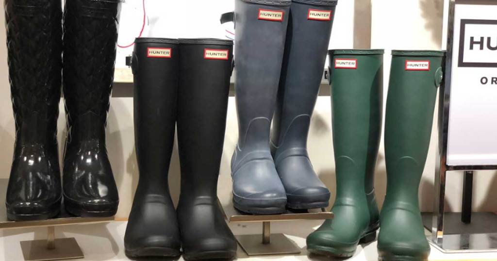 four pairs of tall rain boots on a shelf in a store