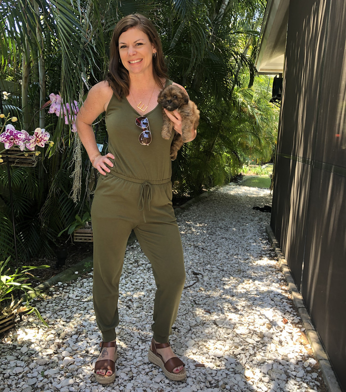 Woman wearing a green jumpsuit for women outside holding a puppy