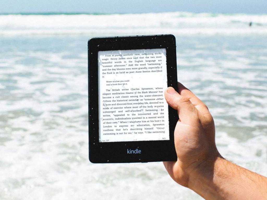 kindle paperwhite being held up over the ocean