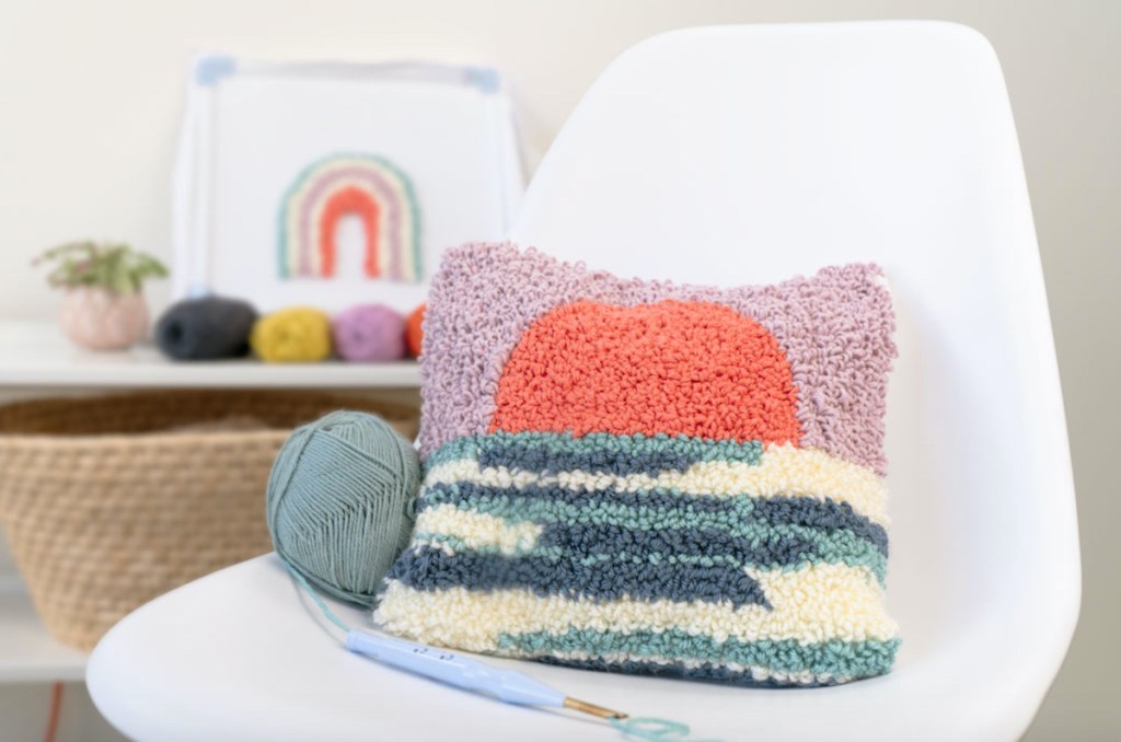 colorful throw pillow and blue yarn sitting on white chair