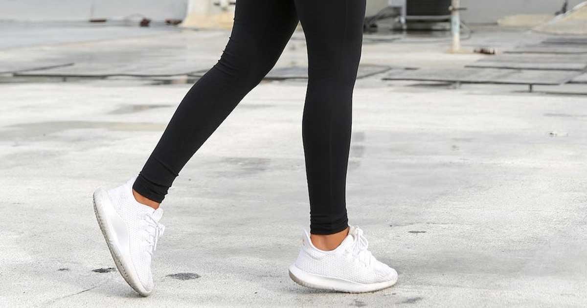 woman wearing a pair of black leggings and white shoes walking in parking lot