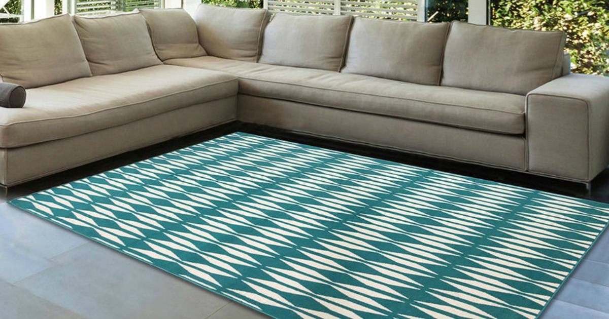 teal and white rug on floor in front of gray couch
