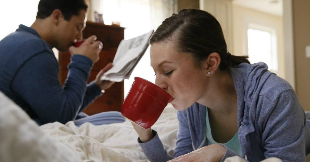 2 people in a bed drinking coffee