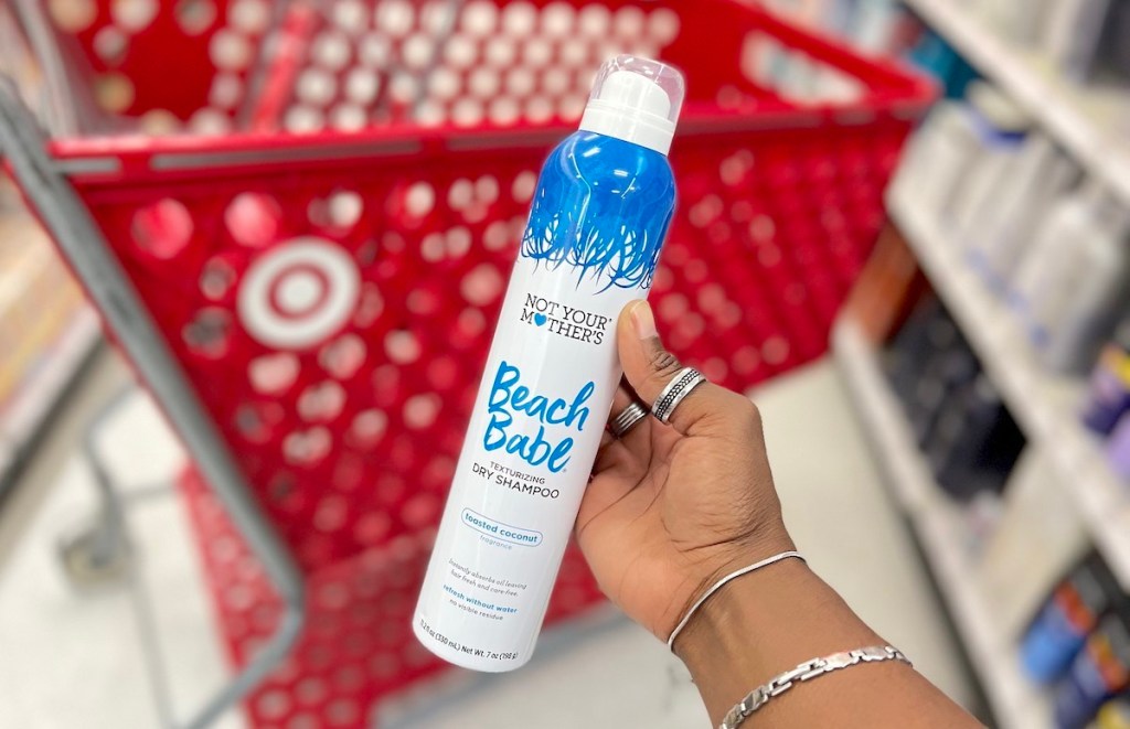 hand holding dry shampoo bottle in front of red target cart