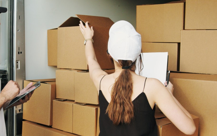 woman touching top of brown moving boxes packing tips for moving