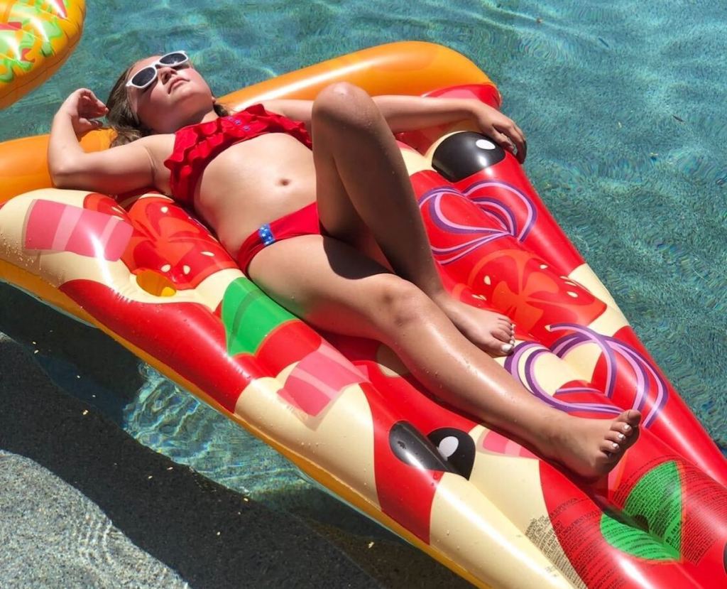 girl laying on pizza pool float in water