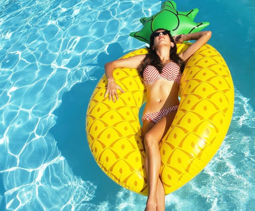woman floating in water on pineapple pool float