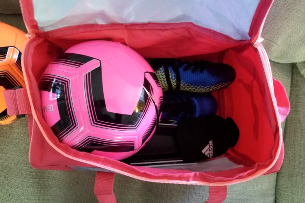 puma duffel opened with soccer ball and cleats in side