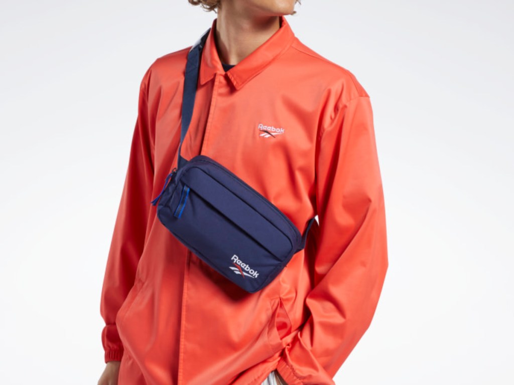 man wearing orange reebok shirt wearing blue reebok waistbag around his neck