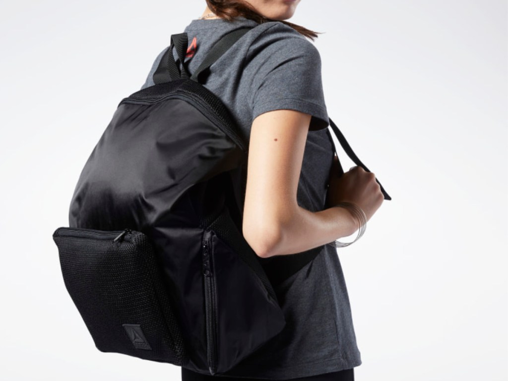 woman wearing gray shirt and black reebok backpack 