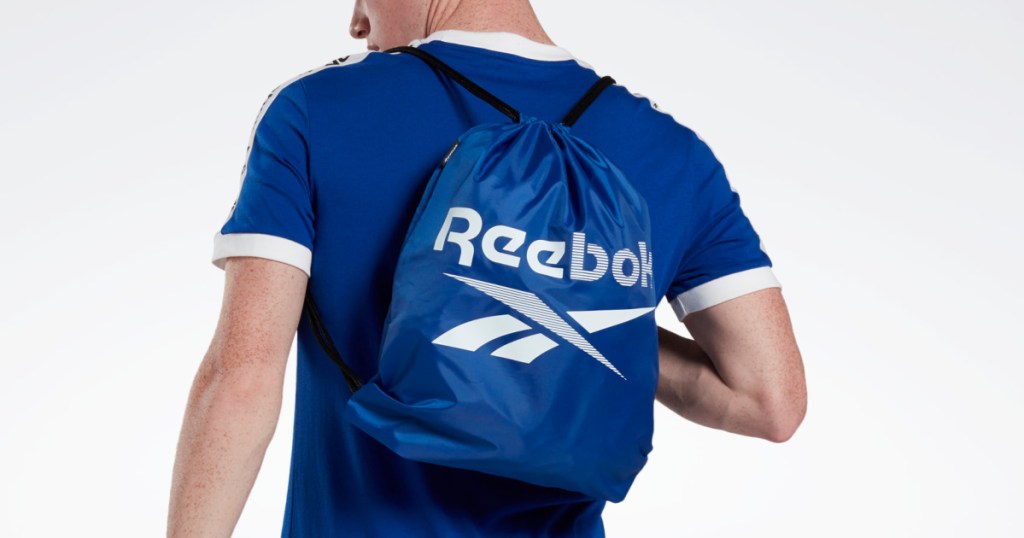 man in blue shirt wearing blue Reebok gym sack 