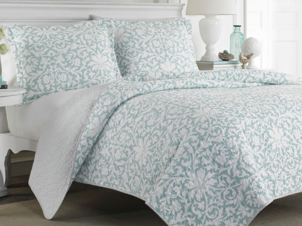 blue and white reversible quilt bedding set on bed in bedroom