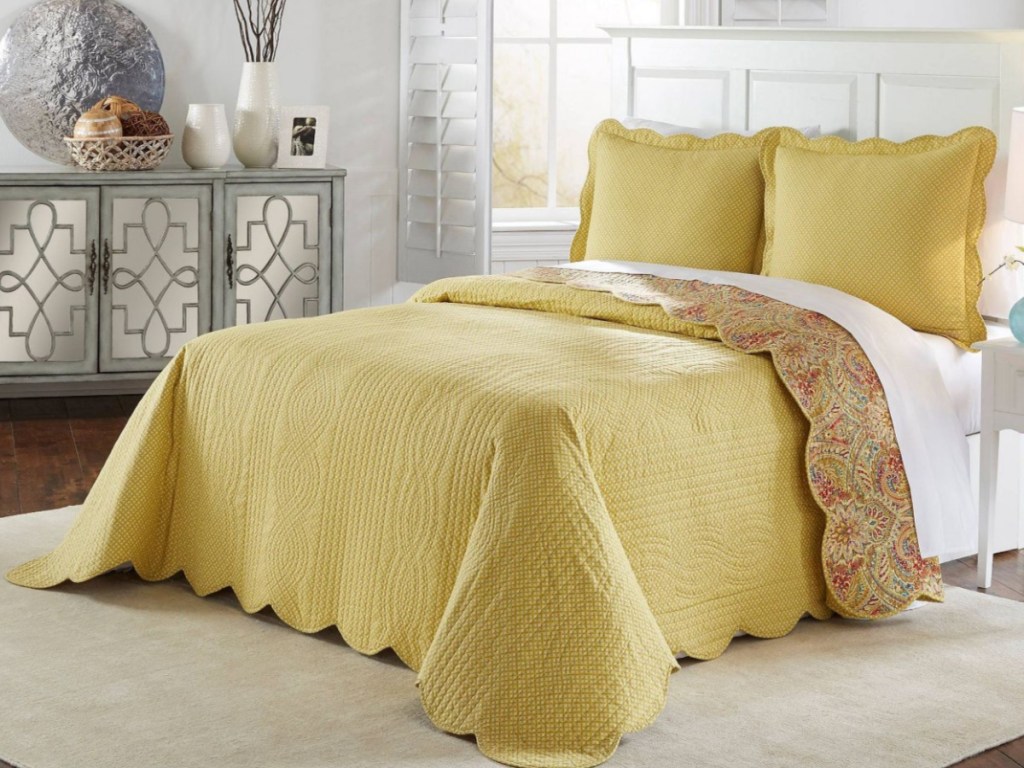 yellow and floral reversible bedspread set on bed in bedroom