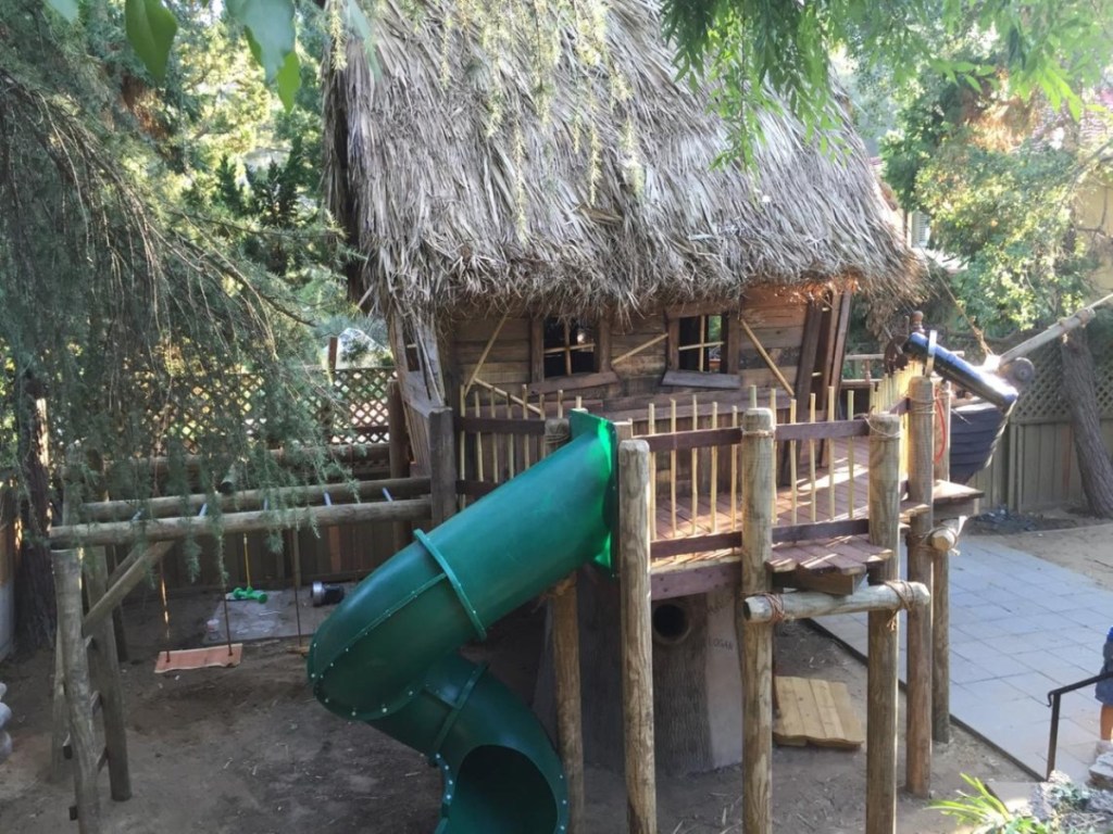 playhouse with tiki roof and green slide