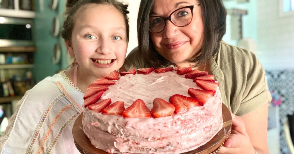 two people holding a starwberry cake