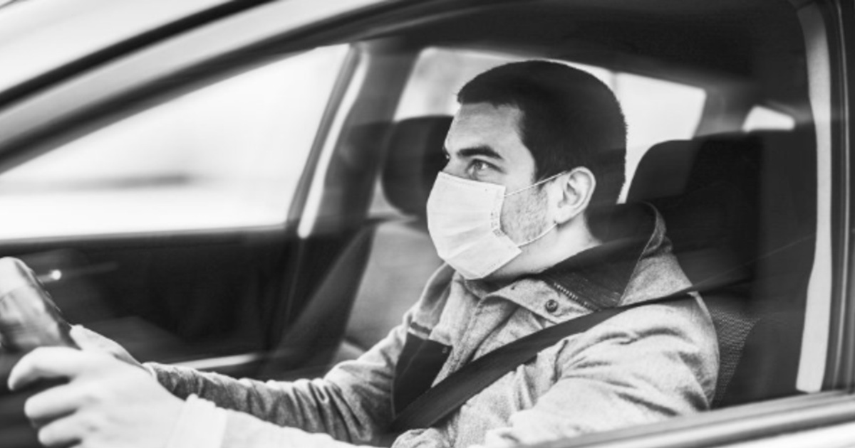 man driving car while wearing a face mask