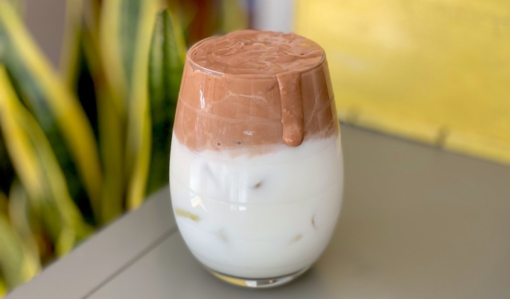 glass sitting on table with half whipped nutella and milk 