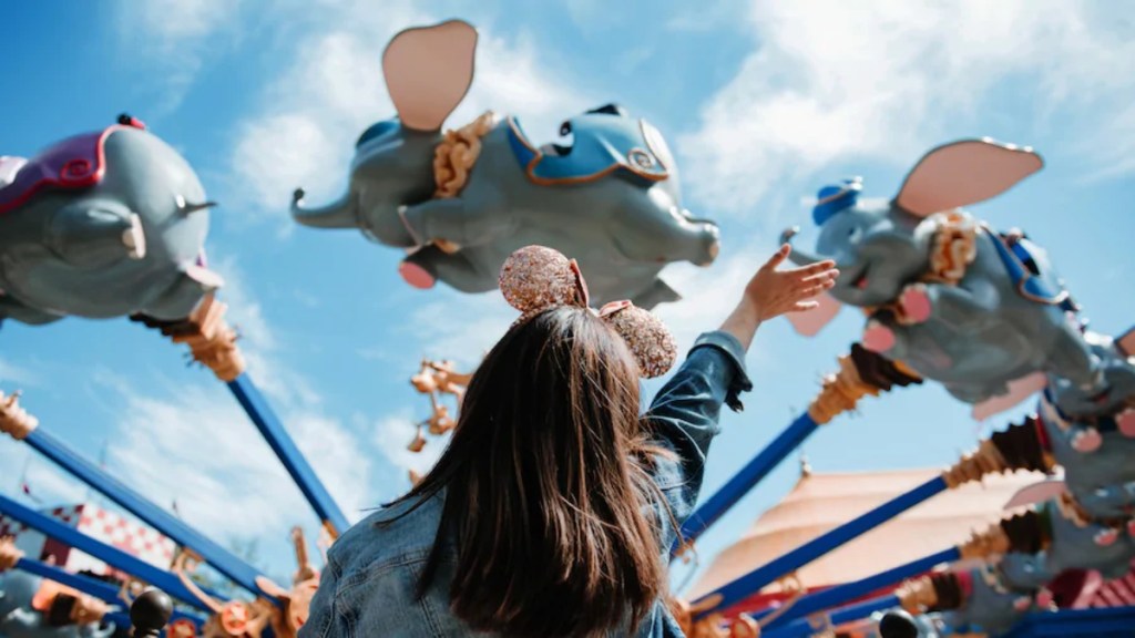 girl with mouse ears waving a Dumbo